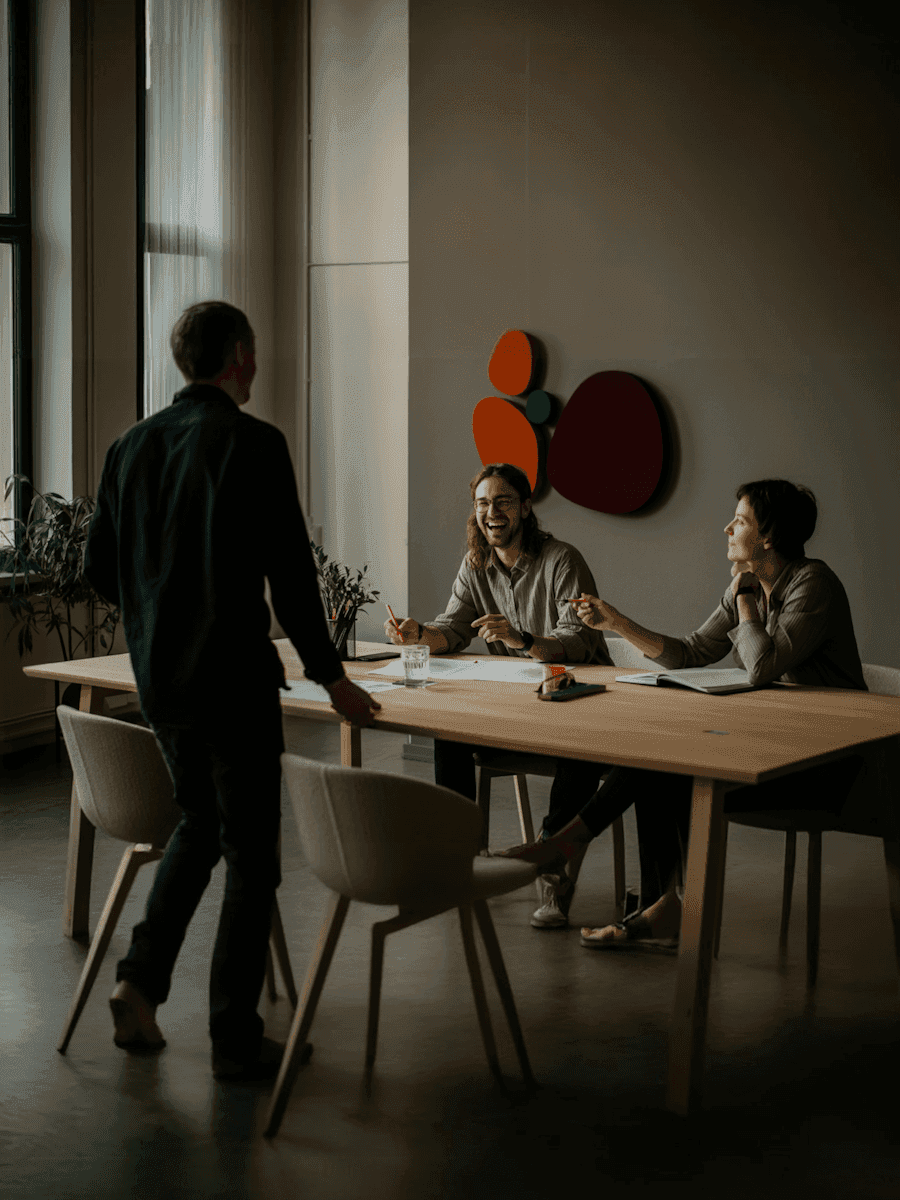 A team meeting around a long wooden table in a bright studio